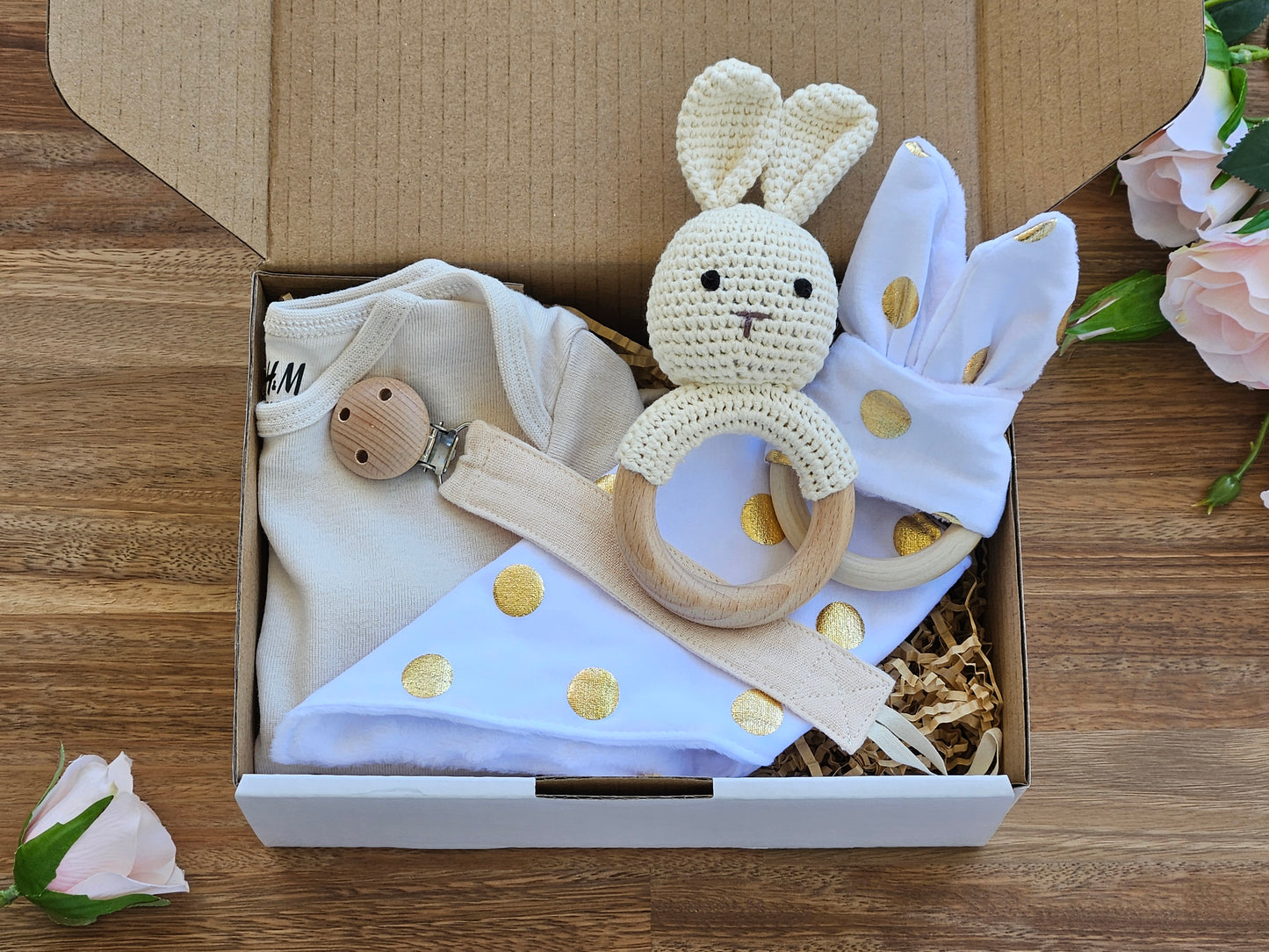 Gift box includes crochet bunny rattle, Romper size 00, cloth pacifier chain, white and gold spotted bandana bib and teether ring toy