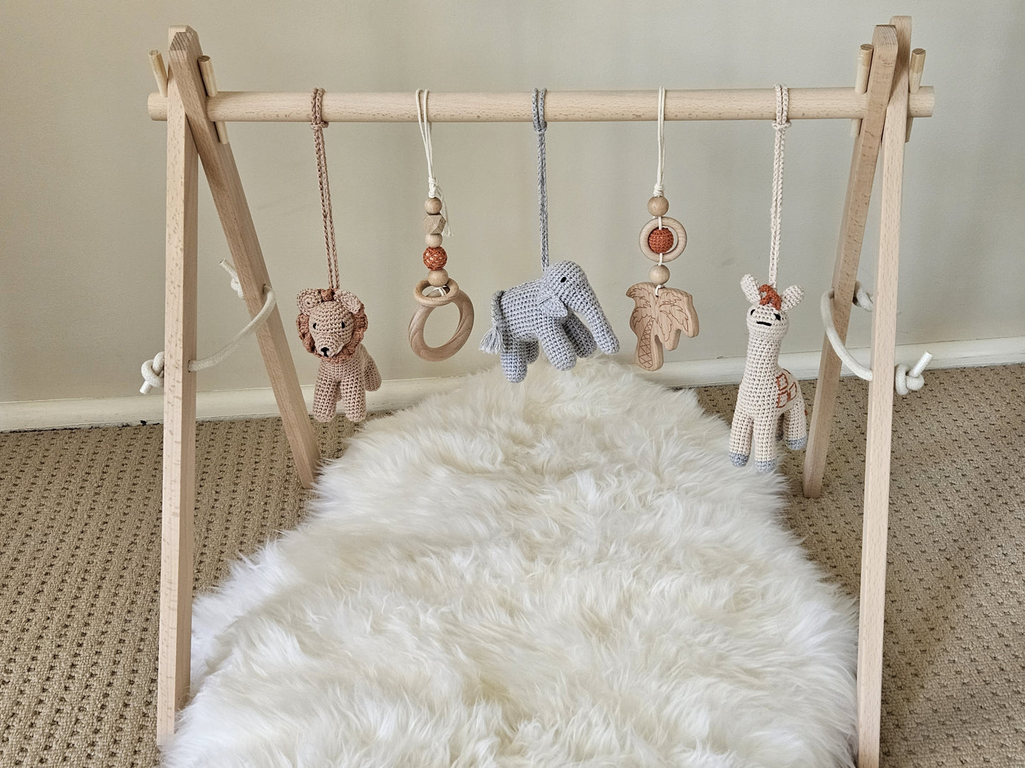 Safari themed wooden baby gym with 5 hanging toys, Crochet beige giraffe, crochet brown lion, crochet grey elephant, 2 wooden hanging toys