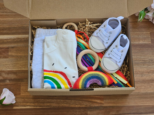 White T_Shirt with rainbow image, grey organic cotton leggings, white jogger shoe, rainbow rattle + ribbon teether ring