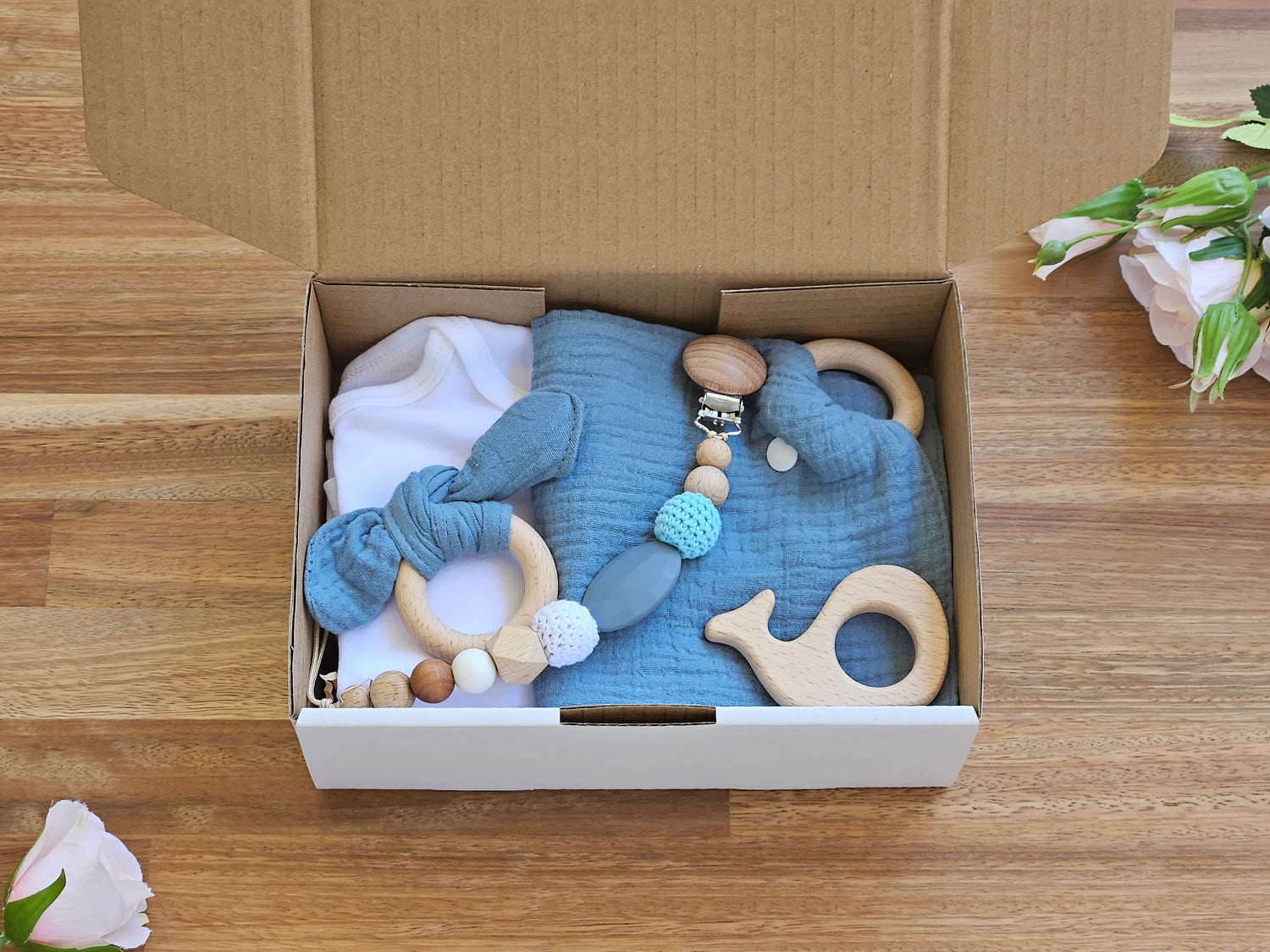 Gift box includes White cotton romper, drool cloth, bunny ear toy ring, beaded pacifier chain and a wooden whale teether toy