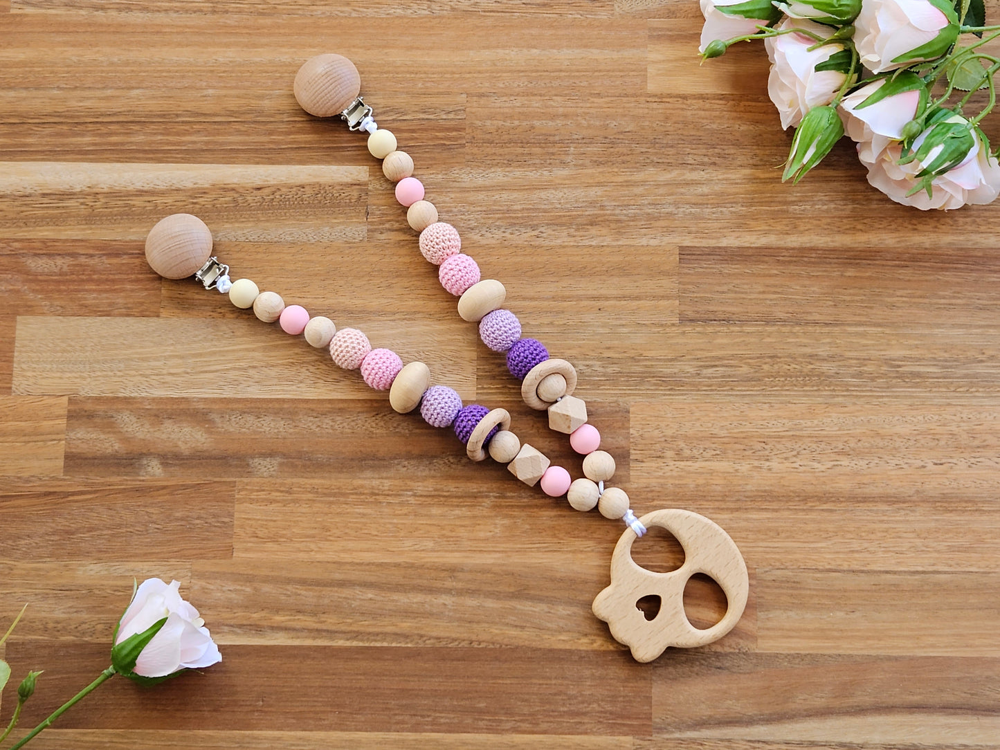 Beaded pram garland toy, includes wooden skull teether toy and is wood, pink and purple colours