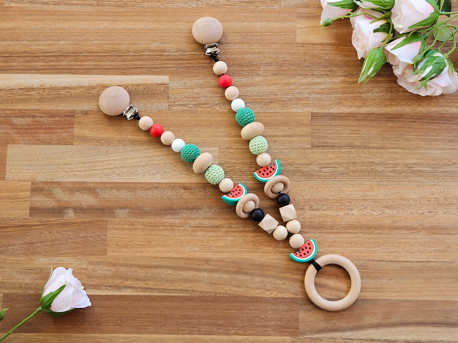 Watermelon themed Beaded pram garland toy, includes wooden ring teether toy and is red, green, white, black colour with 3 slice watermelon beads